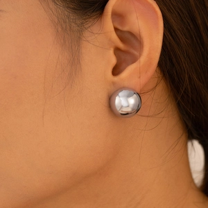 Polished silver sphere stud earrings in stainless steel on a female model