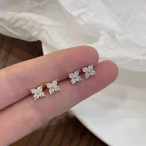 Close-up of gold and silver four-leaf flower stud earrings with sparkling cubic zirconia