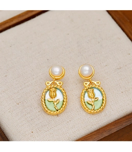 Detailed close-up of French vintage tulip pearl earrings on a textured wooden tray
