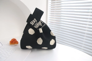 Detail of black polka dot knitted tote bag with Stay Hungry Stay Foolish text on handle