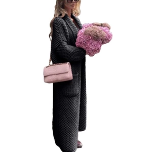Side view of a long black chunky knit cardigan with functional side pockets