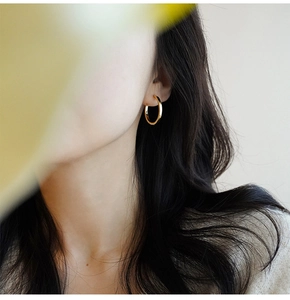 French minimalist gold hoop earrings shown on a model's ear for elegant style