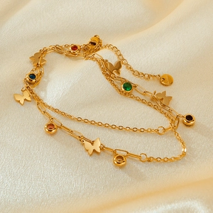 Detail of a gold double-layer butterfly necklace with colorful zircon on beige silk fabric