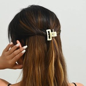 Détail d'une petite pince à cheveux beige mat portée sur cheveux longs en demi-queue