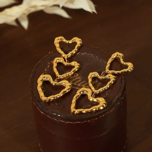 Elegant gold vintage tiered heart earrings with textured geometric design on a leather case