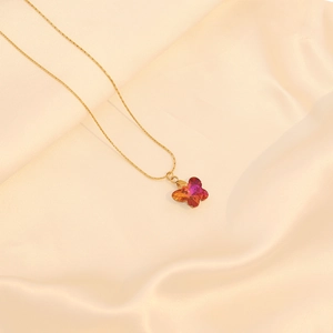 Collier papillon doré avec pendentif dégradé rouge et orange sur tissu en soie beige
