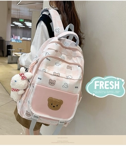 Detail of pink plaid schoolbag featuring cute bear prints and white plush bunny charm