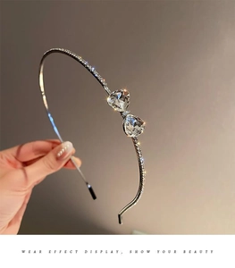Close-up of sparkling rhinestone bow headband with heart detail in silver metal finish