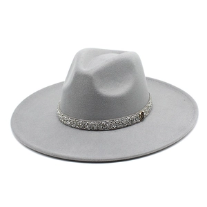 Detail of wide brim grey fedora hat featuring rhinestone band and metallic M logo