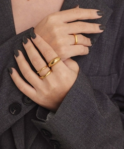 Close-up of minimalist gold plated stainless steel rings styled on a gray blazer