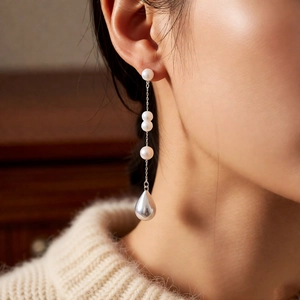 Detail of French vintage pearl drop earrings with long tassels on female model