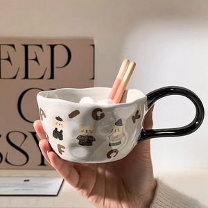 Detail of ceramic bear mug with irregular texture held in hand with marshmallows
