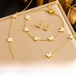 Detail of golden butterfly jewelry set with white shell inlays on necklace and earrings