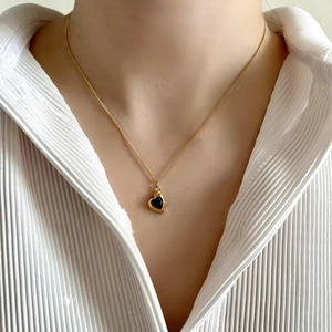Close-up of minimalist black heart pendant with golden edging on model neck