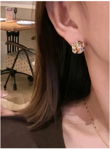 Close-up of a square-cut zirconia earring with colorful facets worn on a model's ear