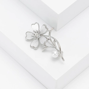 Detail of silver flower brooch with white petals, crystal center and pearl accent