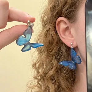 Detailed view of light blue butterfly earrings with glitter on a silver needle hook