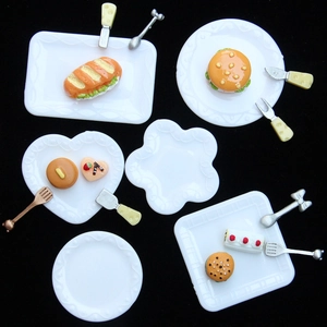 Miniature dollhouse food set with white plates and fake burgers on black background
