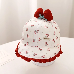 Dettaglio cappello sole neonato con motivi floreali, fiocco rosso e bordo a onde