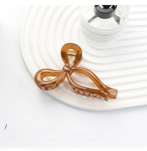 Close-up of elegant amber resin bow hair claw clip with a polished finish and metal spring