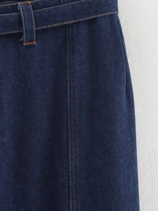 Détail du tissu denim bleu foncé avec coutures orange et boucle de ceinture assortie