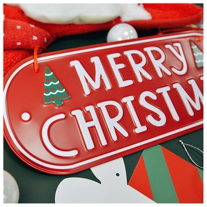 Close-up of red metal Christmas sign with white Merry Christmas embossed lettering