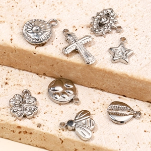 Macro shot of silver stainless steel charms featuring cross, star, and clover designs