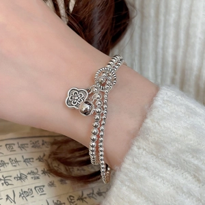 Detailed macro view of a silver flower charm bracelet on a person's wrist with soft knitwear