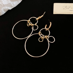 Detail of geometric round drop earrings in gold and silver mixed tones on black background