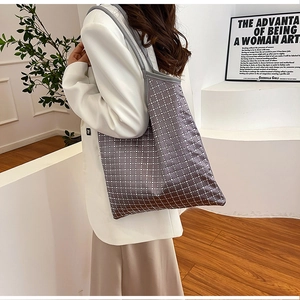 Detail of grey oversized shoulder bag with sparkling diamond-patterned sequins on a model