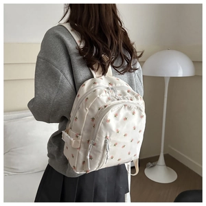 Detail of white floral backpack with pink patterns featuring multiple zip pockets