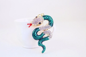 Macro shot of green enamel snake keychain with sparkling rhinestones and gold details