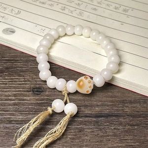 Macro detail of cat paw charm and white beads on a Chinese style braided bracelet