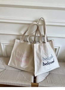 Detail view of embroidered beloved lettering on durable cream canvas tote bag