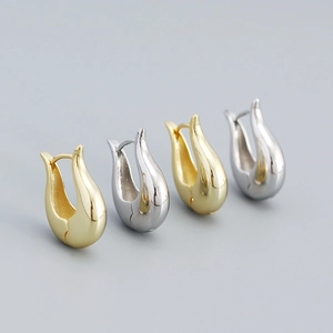 Close-up of minimalist silver and gold U-shaped hoop earrings with a polished metallic finish