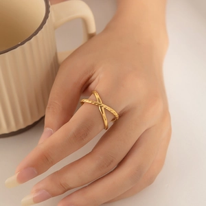 Detail of gold titanium steel X-shaped ring with twisted rope and smooth band textures