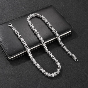 Detailed view of silver stainless steel byzantine chain with lobster clasp on a notebook