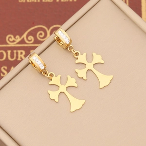 Macro detail of gold cross earrings with white zircon pavé on jewelry box