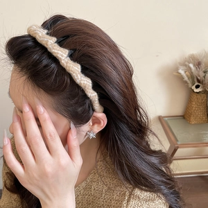 Close-up of brown knitted twist headband with textured wool and snowflake earring accessory