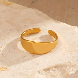 Minimalist golden stainless steel open ring displayed on a natural textured stone base