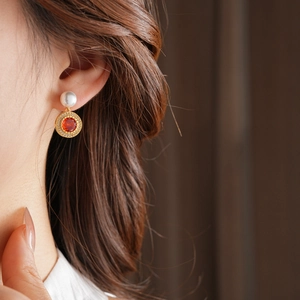 Vue rapprochée de boucles d'oreilles dorées avec perles blanches et cristaux rouges