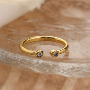 Macro shot of gold-plated open ring with deep blue zircon stones on textured glass