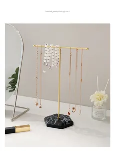 Detailed close-up of T-bar jewelry stand with gold metal finish and marble hexagon base
