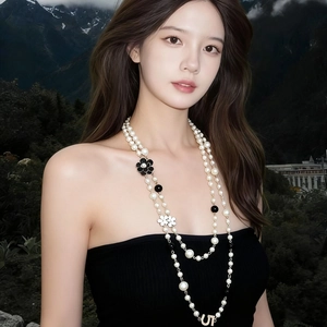 Long layered pearl necklace featuring camellia flowers and a golden letter pendant