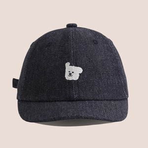 Gros plan sur la broderie de chiot blanc sur une casquette en jean bleu foncé pour enfants