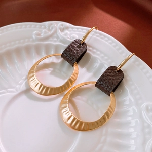 Vintage geometric gold hammered circle earrings with dark brown leather accents on silk