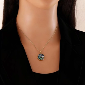 Détail d'un collier vintage doré avec pendentif fleur bleue et perle porté sur un mannequin