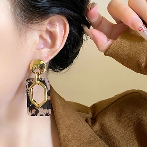 Close-up of retro leopard print resin earrings with golden hexagonal metal details