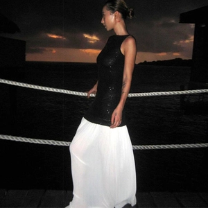 Detail of sequined sleeveless top and white pleated maxi dress on a seaside boardwalk