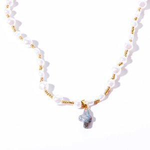 Détail d'un collier en perles baroques avec un pendentif en nacre en forme de croix dorée